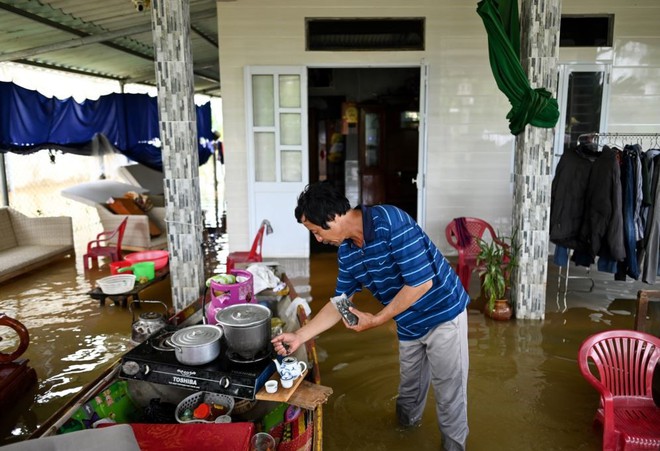 24h qua ảnh: Người đàn ông pha trà trong ngôi nhà ngập lụt ở Việt Nam - Ảnh 2.
